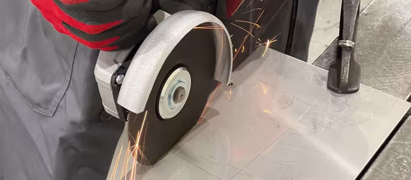 Bild på person som kapar en metallplåt med hjälp av en armerad kapskiva